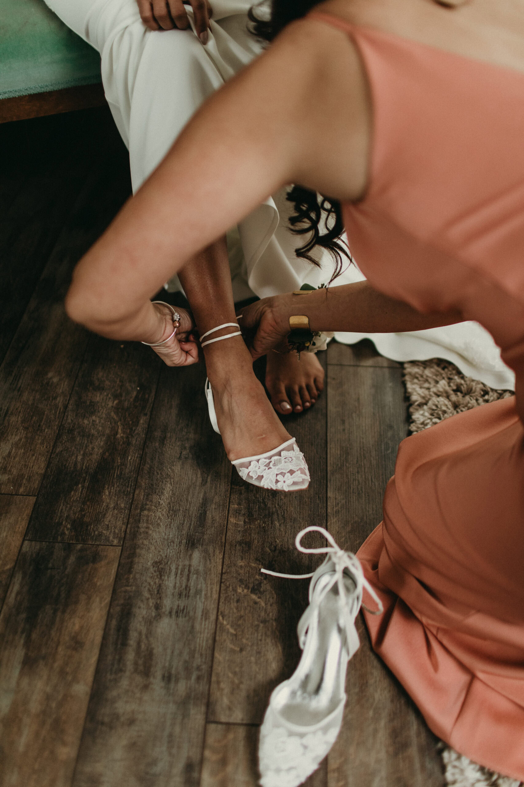 Elegant white wedding shoes being adjusted on bride's feet.