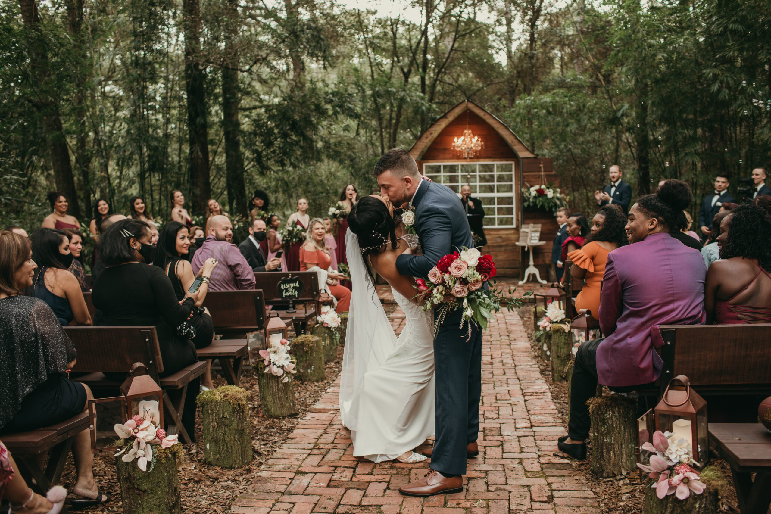 Elegant outdoor wedding ceremony with bride and groom exchanging vows in a forest setting.