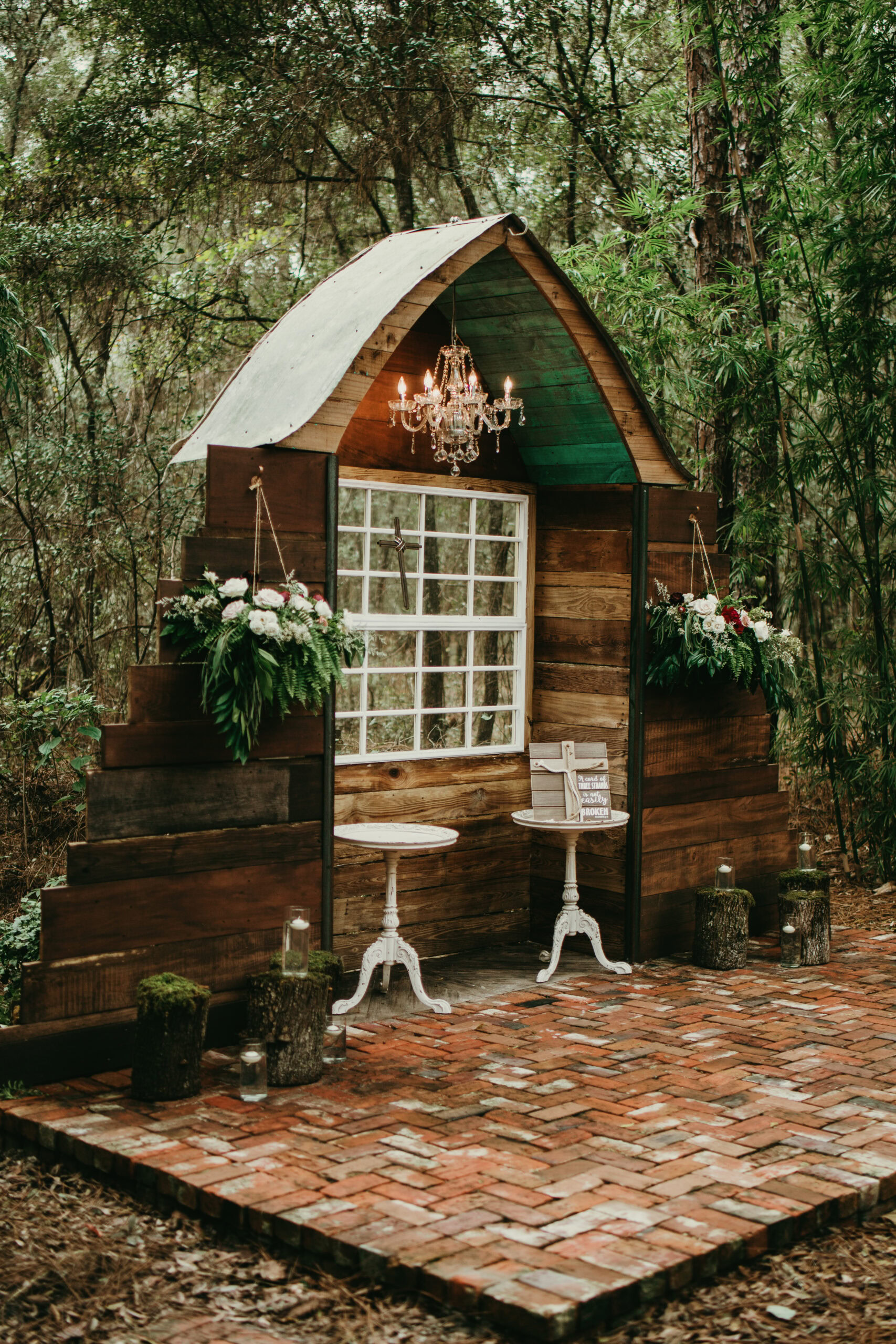 Elegant rustic wedding photo booth setup in a forest setting.
