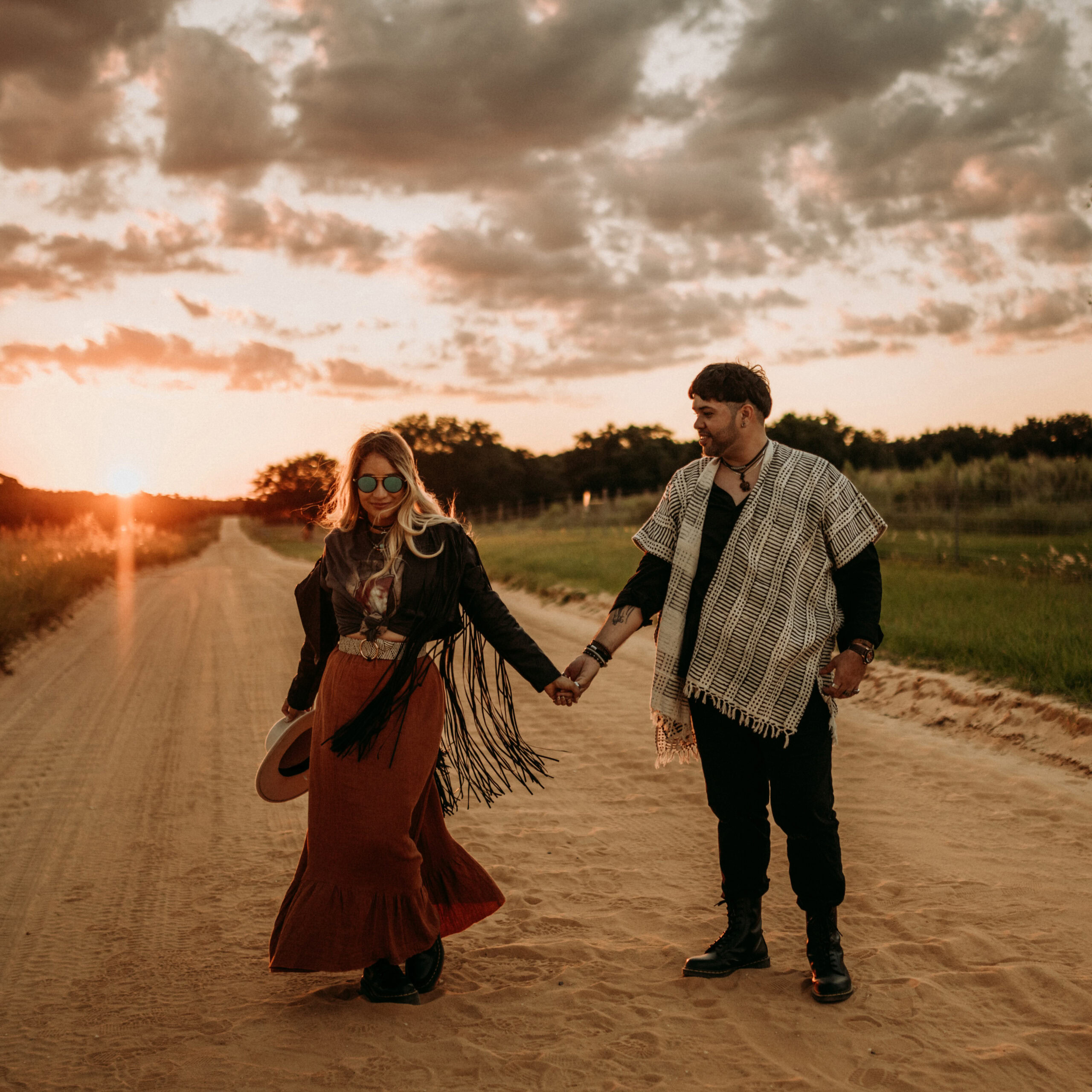 Angie & Marko holding hands during sunset on a dirt road, enjoying a romantic moment in nature.